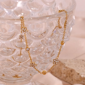 Macro shot of gold necklace with zircon flowers and round beads on glass bowl