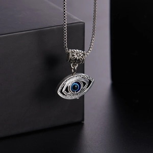 Detailed close-up of a silver devil eye pendant with blue inlay on a box chain necklace