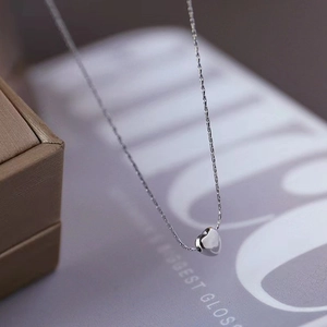 Macro view of polished heart pendant and refined link chain in silver finish