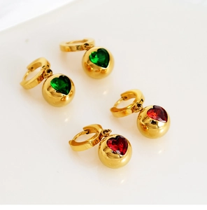 Détail de boucles d'oreilles boules dorées avec zircons en forme de cœur vert et rouge