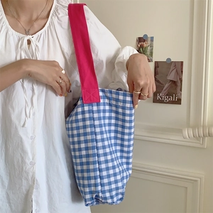Blue and white gingham canvas tote bag with pink straps shown in a lifestyle setting