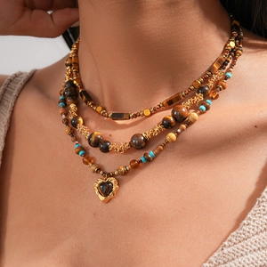 Close-up of bohemian layered tiger eye bead necklace with a gold heart pendant charm