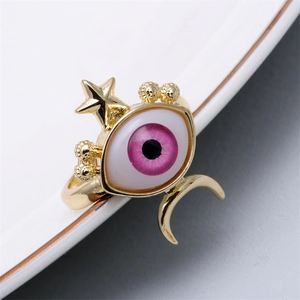 Detail view of gold ring featuring pink-purple evil eye with moon and star accents