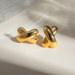 Detailed macro view of 18k gold plated stainless steel X-shaped earrings with mirror finish