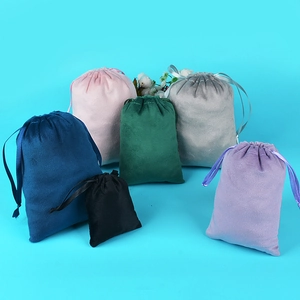 Various colored drawstring velvet jewelry pouches displayed on a teal blue background