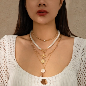 Detail of layered beach necklace with faux pearls and golden starfish shell pendants