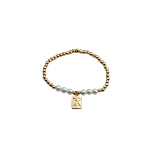 Detail of beaded bracelet with gold copper beads, white pearls, and letter X pendant