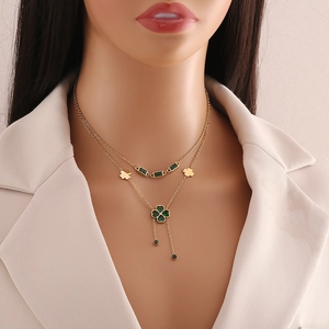 Double-layered golden necklace with emerald butterfly and clover pendants on model