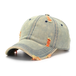 Detail of distressed light blue denim baseball cap with orange and yellow frayed holes