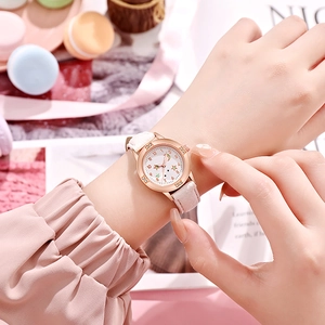 Gros plan d'une montre femme or rose avec cadran étoilé et bracelet en cuir rose
