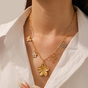 Detail view of gold floral and butterfly pendant necklace on a minimalist model