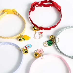 Macro view of five colorful fabric pet collars with gold bells and enamel charms