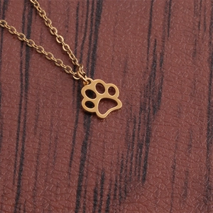 Polished gold dog paw pendant necklace in stainless steel on brown leather background