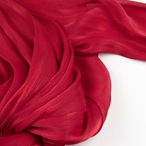Close-up of red pleated fabric texture on waist-slimming dress with detailed vertical folds
