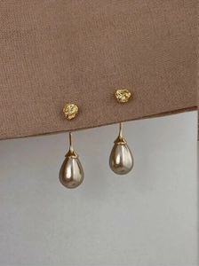 Detailed close-up of champagne teardrop pearl earrings with hammered gold metal texture