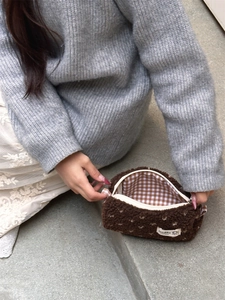 Détail de la trousse en peluche marron montrant la doublure à carreaux et le zip