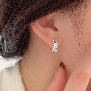 Close-up of 925 sterling silver croissant hoop earrings on model showing spiral texture