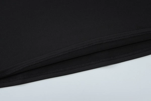 Detailed close-up of double-needle hem stitching on black cotton knit dress fabric