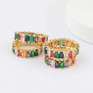 Close-up of stacked gold eternity rings featuring multi-colored rectangular gemstones