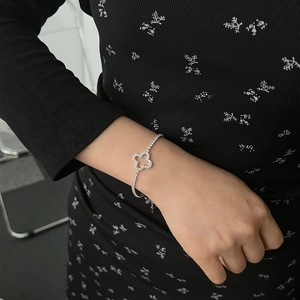 Macro detail of S925 silver tennis bracelet with zircon clover and pavé diamonds