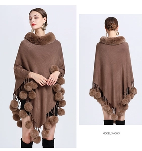 Detailed view of brown knit poncho with faux fur collar and decorative pom-pom tassels