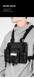 Front view of black tactical chest bag with reflective strips and multiple buckles on model