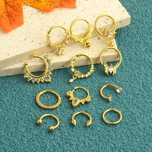 Macro detail of gold stainless steel piercing set with zircon accents and bee charms