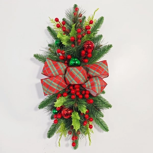 Christmas teardrop swag with green pine, red berries and a large plaid bow on white background