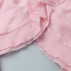 Detail showing tiered ruffles and light pink pleated texture on sleeveless summer top