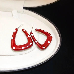 Macro shot of red triangular earrings with white polka dots and silver needle pins