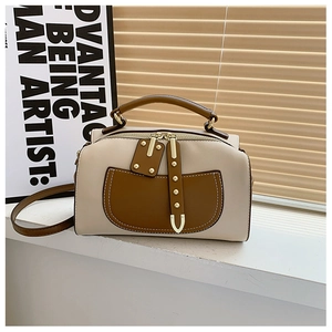 Gros plan du sac Boston en cuir bicolore avec rivets dorés et double fermeture éclair
