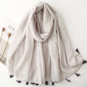 Close-up of light gray cotton linen shawl with silver sequins and purple tassel accents