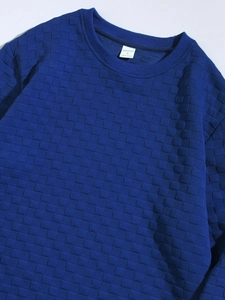 Detail of dark blue men's sweater showing 3D checkerboard texture and inner label