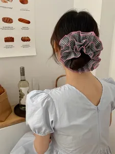 Close-up of oversized black and white checkered scrunchie with pink ruffle trim on hair