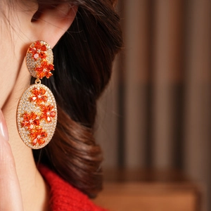 Close-up of vintage floral drop earrings with orange stones and zircon insets on a model