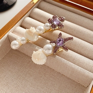 Détail de barrettes à thème marin avec étoile de mer violette et perles sur un coffret