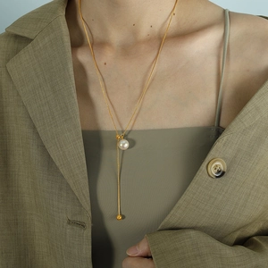 Verstellbare Schlangenkette in Gold mit Glasperlenanhänger auf grünem Stoff getragen