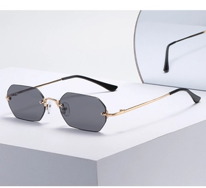 Detalle de gafas de sol octogonales sin montura con lentes grises y montura dorada