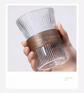 Detail of a fluted glass cup featuring a walnut wood anti-scald sleeve with engraving