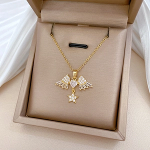 Macro view of gold star and wing pendant necklace with pavé cubic zirconia in a jewelry box