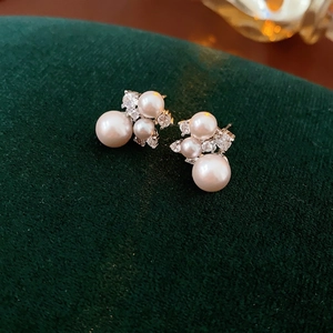 Exquisite silver needle cluster pearl earrings with zircon accents on green velvet