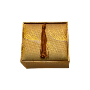 Square gold jewelry box with feather pattern fabric and dark brown tassel decoration