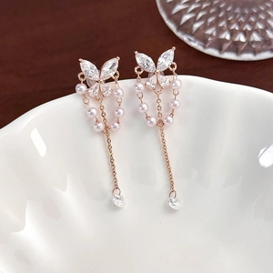 Detailed close-up of rose gold butterfly earrings with zircon crystals and small pearls