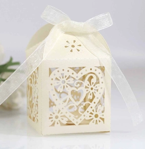 Intricate laser-cut wedding favor box with heart patterns and a white ribbon bow