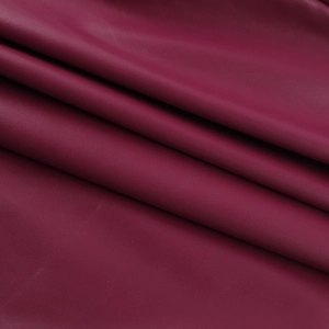 Texture détaillée du similicuir bordeaux avec des plis doux et une surface grainée