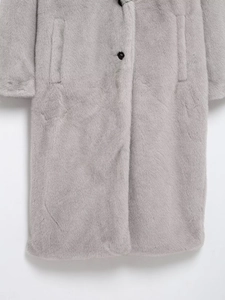 Detailed close-up of fluffy faux fur texture and black button on grey long winter coat