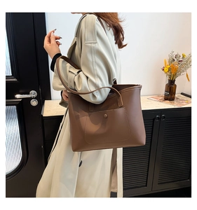 Detailed view of a brown tote bag with external pocket on a model in trench coat