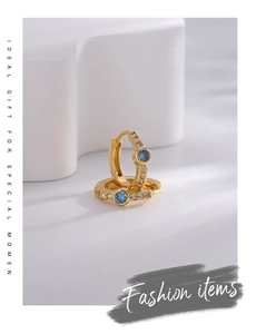 Detail of gold hoop earrings with central blue zircon and white diamond pave accents