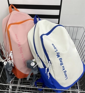 Detail of trendy color-block backpacks in a metal basket with cute doll pendants