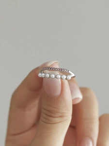 Gros plan d'une bague double couche avec zircons roses et perles blanches à la main